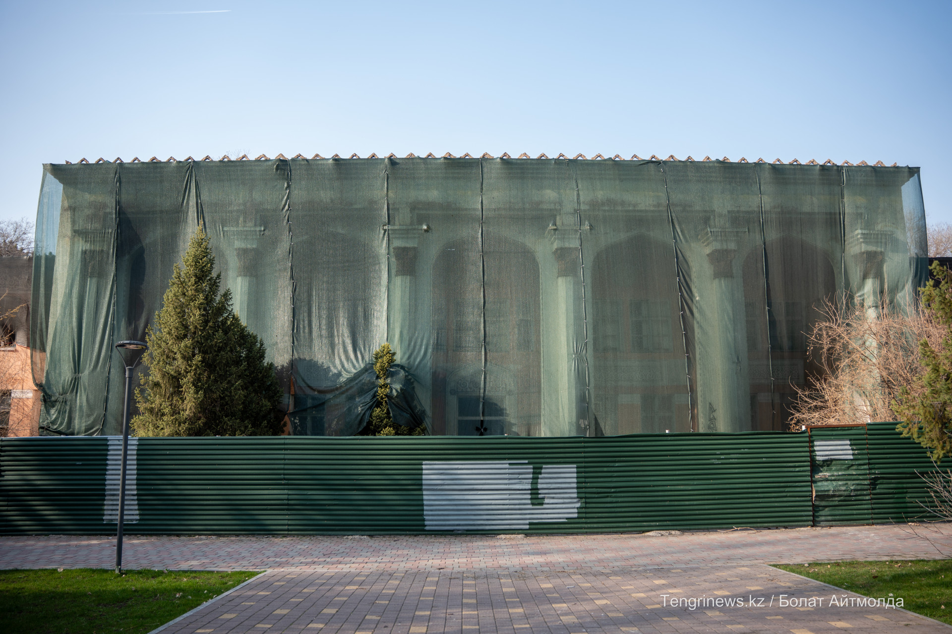 Зеленый забор и строительная сетка вокруг здания бывшей железно-дорожной больницы в Алматы